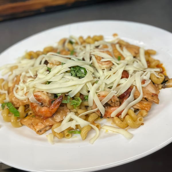 Jo-Jo's Italian Grille's pasta dish with chicken, shrimp, and shredded cheese on a white plate.
