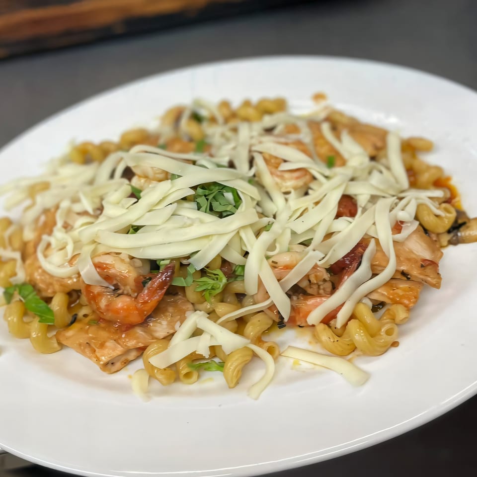 Jo-Jo's Italian Grille's pasta dish with chicken, shrimp, and shredded cheese on a white plate.